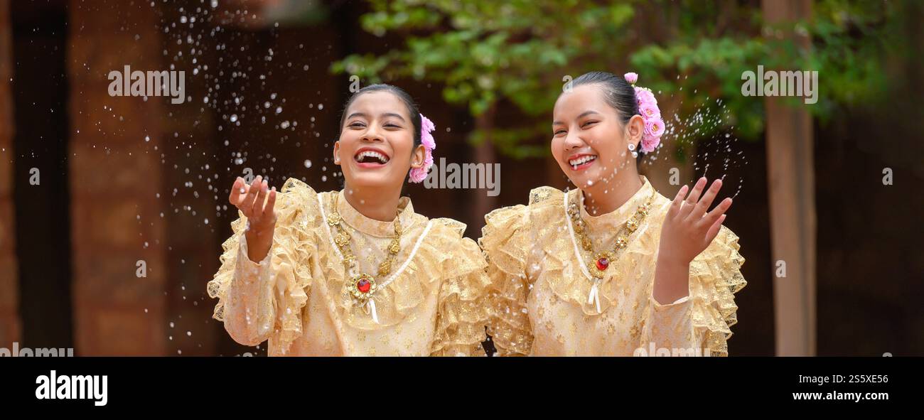 Les jeunes femmes souriantes s'habillent de beaux costumes thaïlandais éclaboussant de l'eau dans les temples et préservant la bonne culture du peuple thaïlandais pendant Songkran Banque D'Images