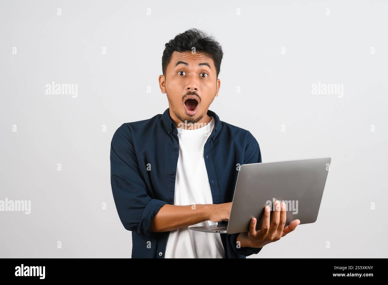 Portrait d'homme d'affaires asiatique choqué travaillant sur ordinateur portable isolé sur fond blanc. Technologie, commerce et concept d'éducation. Banque D'Images