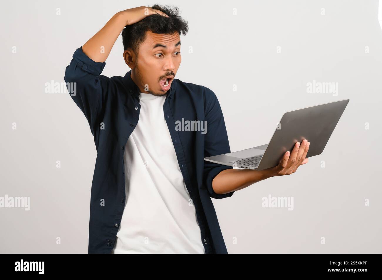 Portrait d'homme d'affaires asiatique choqué travaillant sur ordinateur portable isolé sur fond blanc. Technologie, commerce et concept d'éducation. Banque D'Images