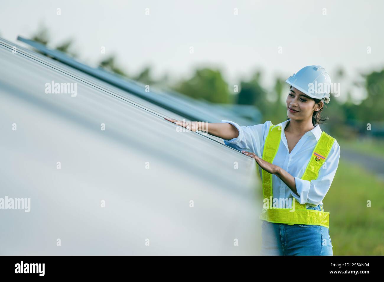 Portrait asiatique jeune femme ingénieur portant des vêtements de protection et casque blanc debout près de panneaux solaires tout en travaillant dans la ferme solaire, à la recherche Banque D'Images