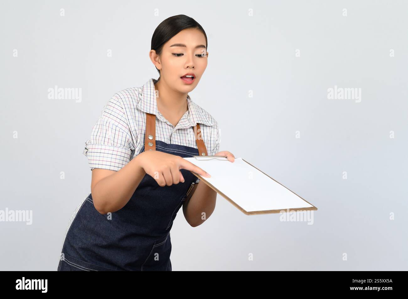 Portrait de jeune femme asiatique en uniforme de serveuse tenant maquette de presse-papiers avec stylo, espace de copie pour insérer du texte pour la publicité isolé sur blanc Banque D'Images