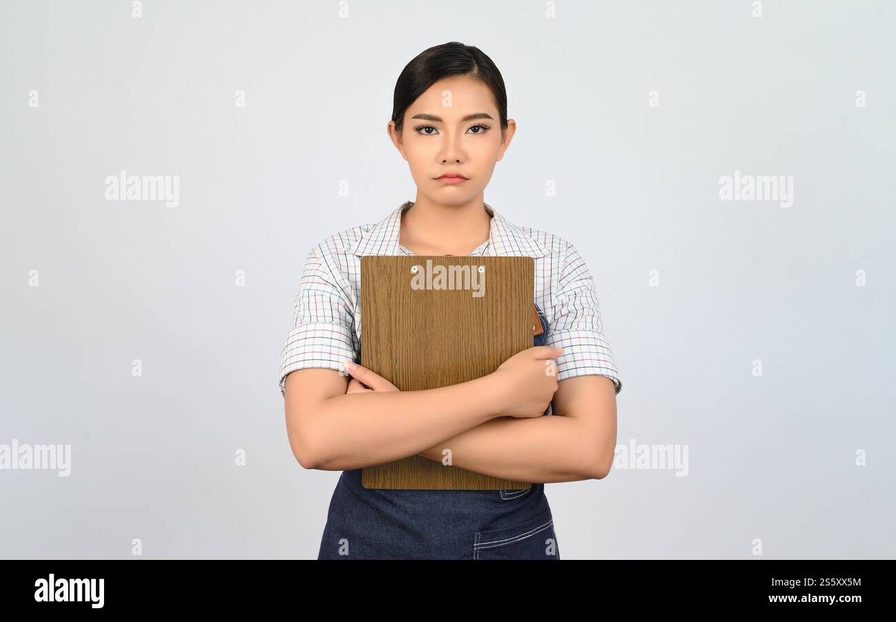 Portrait de jeune femme asiatique dans l'uniforme de serveuse tenant le presse-papiers pour vérifier l'ordre, copier l'espace pour insérer des produits pour la publicité isolé sur Banque D'Images