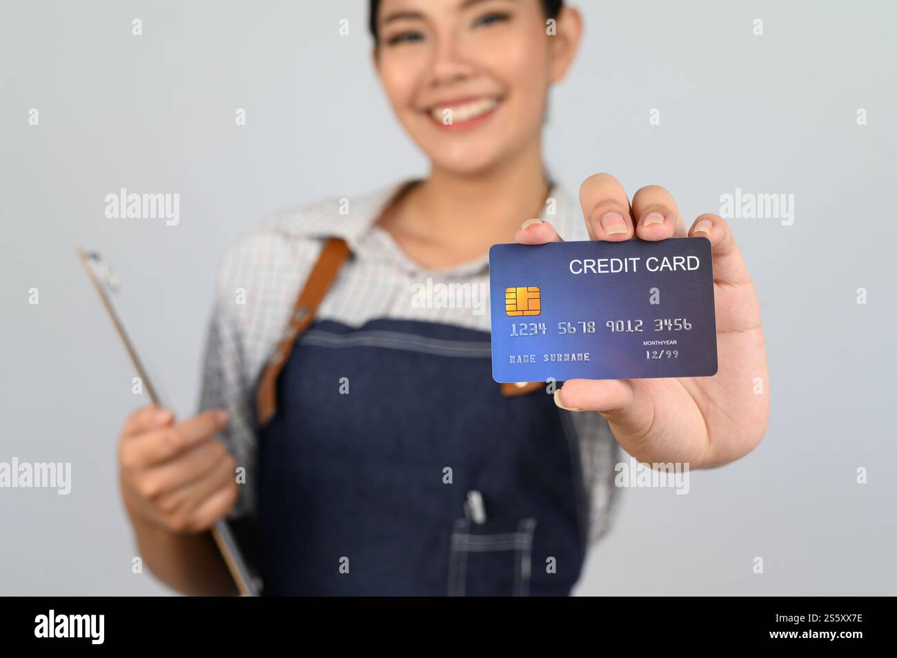 Focus sélectif, carte de crédit en main de jeune femme asiatique en uniforme de serveuse montrant la pose, espace de copie pour insérer des produits pour la publicité isolé Banque D'Images