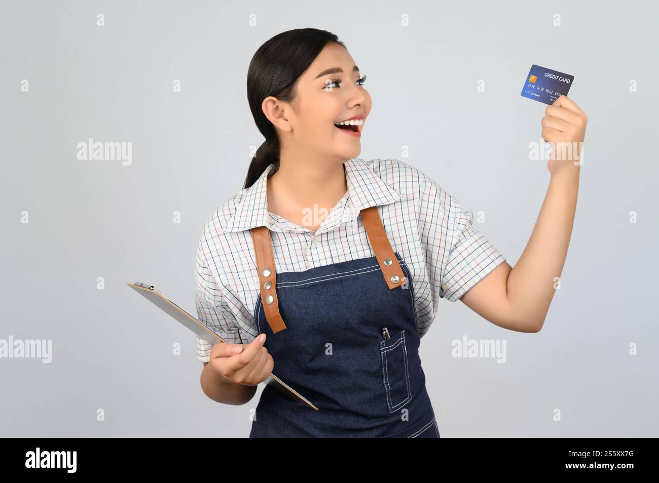 Portrait de jeune femme asiatique dans la pose uniforme de serveuse avec la carte de crédit à la main, copier l'espace pour insérer des produits pour la publicité isolé sur blanc Banque D'Images