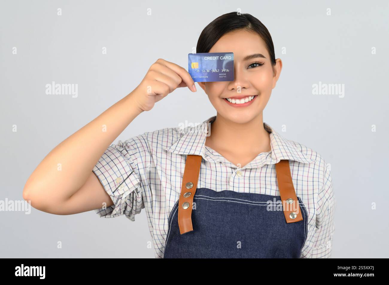Portrait de jeune femme asiatique dans la pose uniforme de serveuse avec la carte de crédit à la main, copier l'espace pour insérer des produits pour la publicité isolé sur blanc Banque D'Images
