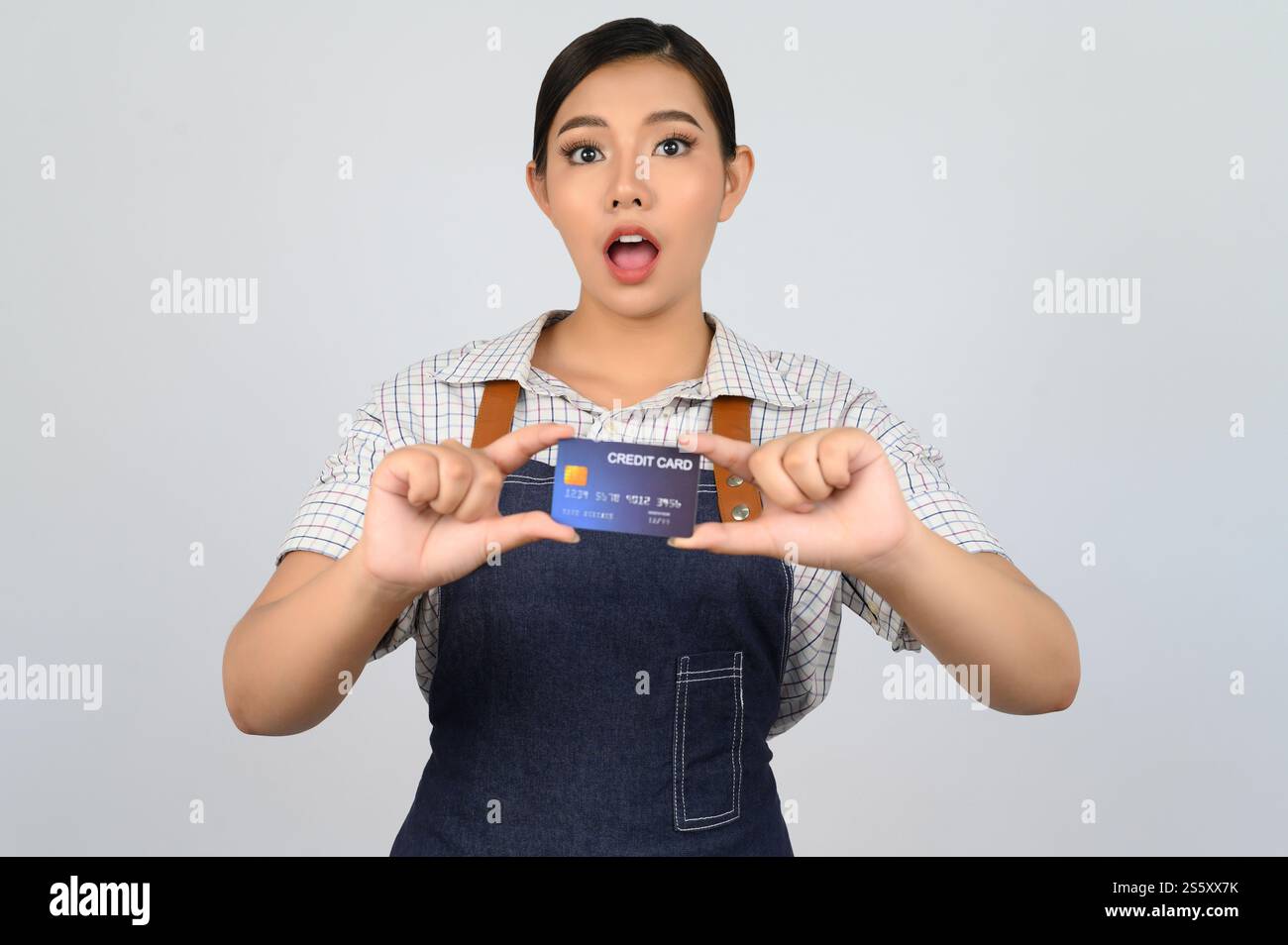Portrait de jeune femme asiatique dans la pose uniforme de serveuse avec la carte de crédit à la main, copier l'espace pour insérer des produits pour la publicité isolé sur blanc Banque D'Images