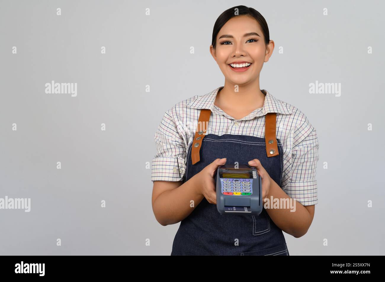 Portrait de jeune femme asiatique dans la pose uniforme de serveuse avec carte de crédit et lecteur de carte de crédit machine à la main, espace de copie pour insérer des produits pour Banque D'Images