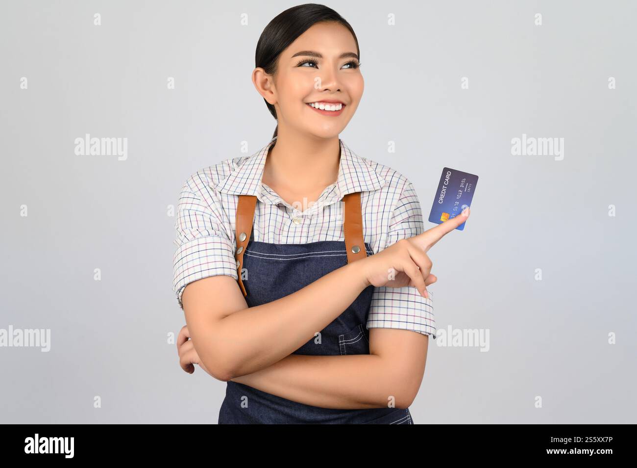 Portrait de jeune femme asiatique dans la pose uniforme de serveuse avec la carte de crédit à la main, copier l'espace pour insérer des produits pour la publicité isolé sur blanc Banque D'Images