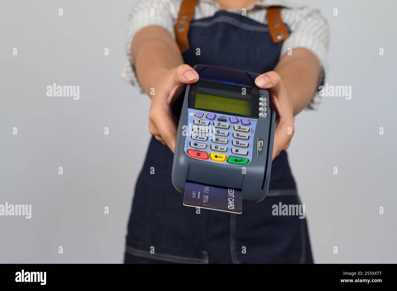 Mains de la jeune femme asiatique dans la pose uniforme de serveuse avec carte de crédit et machine de lecteur de carte de crédit, espace de copie pour insérer des produits pour la publicité Banque D'Images