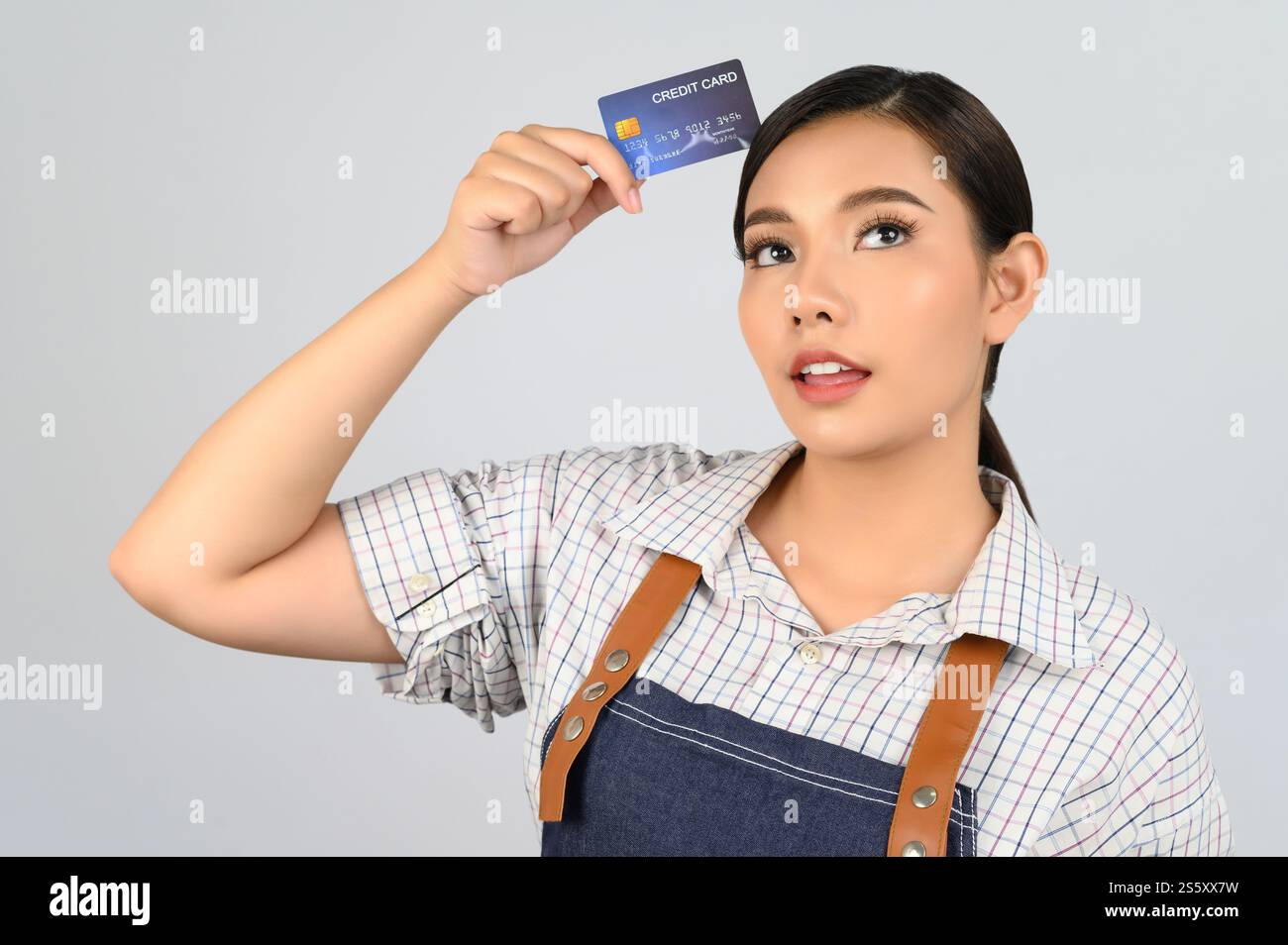 Portrait de jeune femme asiatique dans la pose uniforme de serveuse avec la carte de crédit à la main, copier l'espace pour insérer des produits pour la publicité isolé sur blanc Banque D'Images