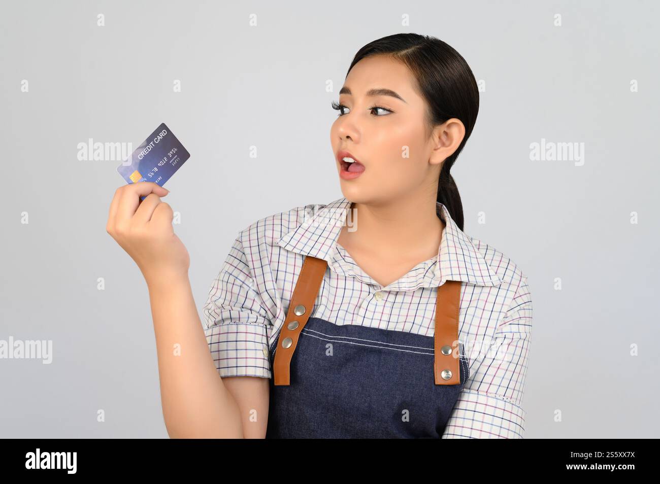 Portrait de jeune femme asiatique dans la pose uniforme de serveuse avec la carte de crédit à la main, copier l'espace pour insérer des produits pour la publicité isolé sur blanc Banque D'Images