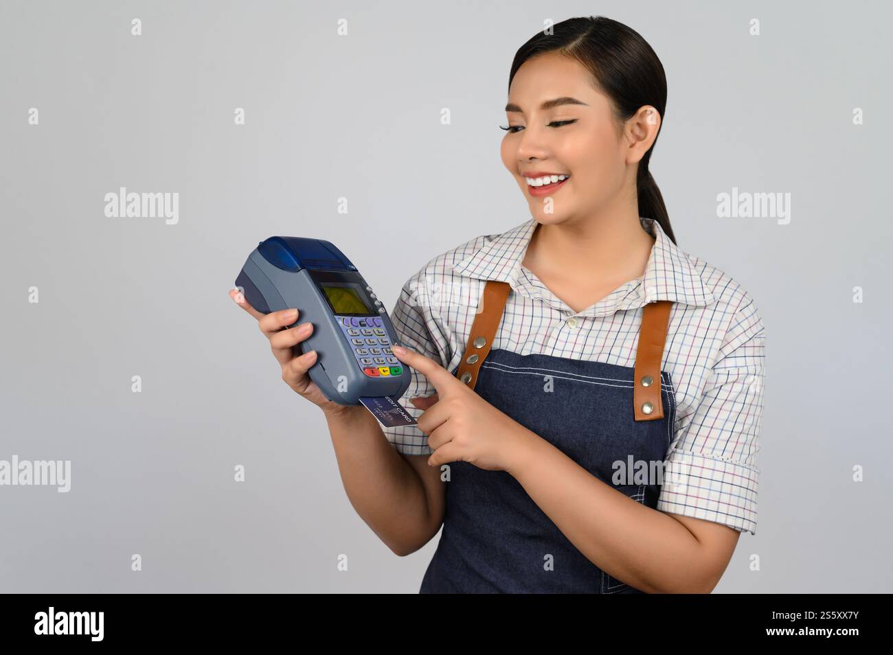 Portrait de jeune femme asiatique dans la pose uniforme de serveuse avec carte de crédit et lecteur de carte de crédit machine à la main, espace de copie pour insérer des produits pour Banque D'Images