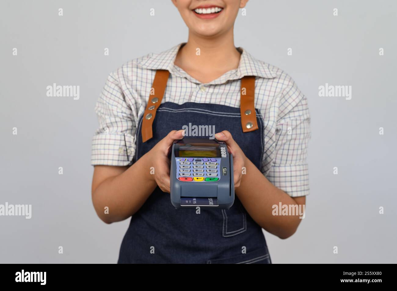 Portrait de jeune femme asiatique dans la pose uniforme de serveuse avec carte de crédit et lecteur de carte de crédit machine à la main, espace de copie pour insérer des produits pour Banque D'Images