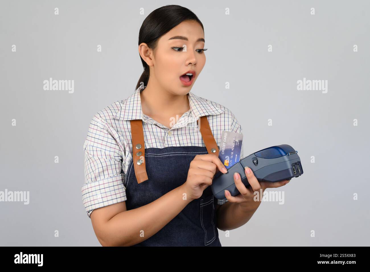 Portrait de jeune femme asiatique dans la pose uniforme de serveuse avec carte de crédit et lecteur de carte de crédit machine à la main, espace de copie pour insérer des produits pour Banque D'Images