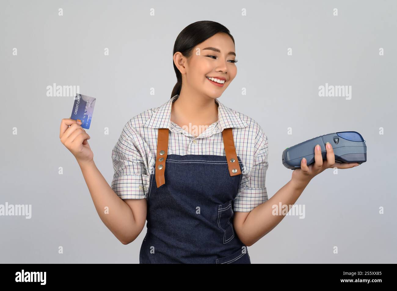 Portrait de jeune femme asiatique dans la pose uniforme de serveuse avec carte de crédit et lecteur de carte de crédit machine à la main, espace de copie pour insérer des produits pour Banque D'Images