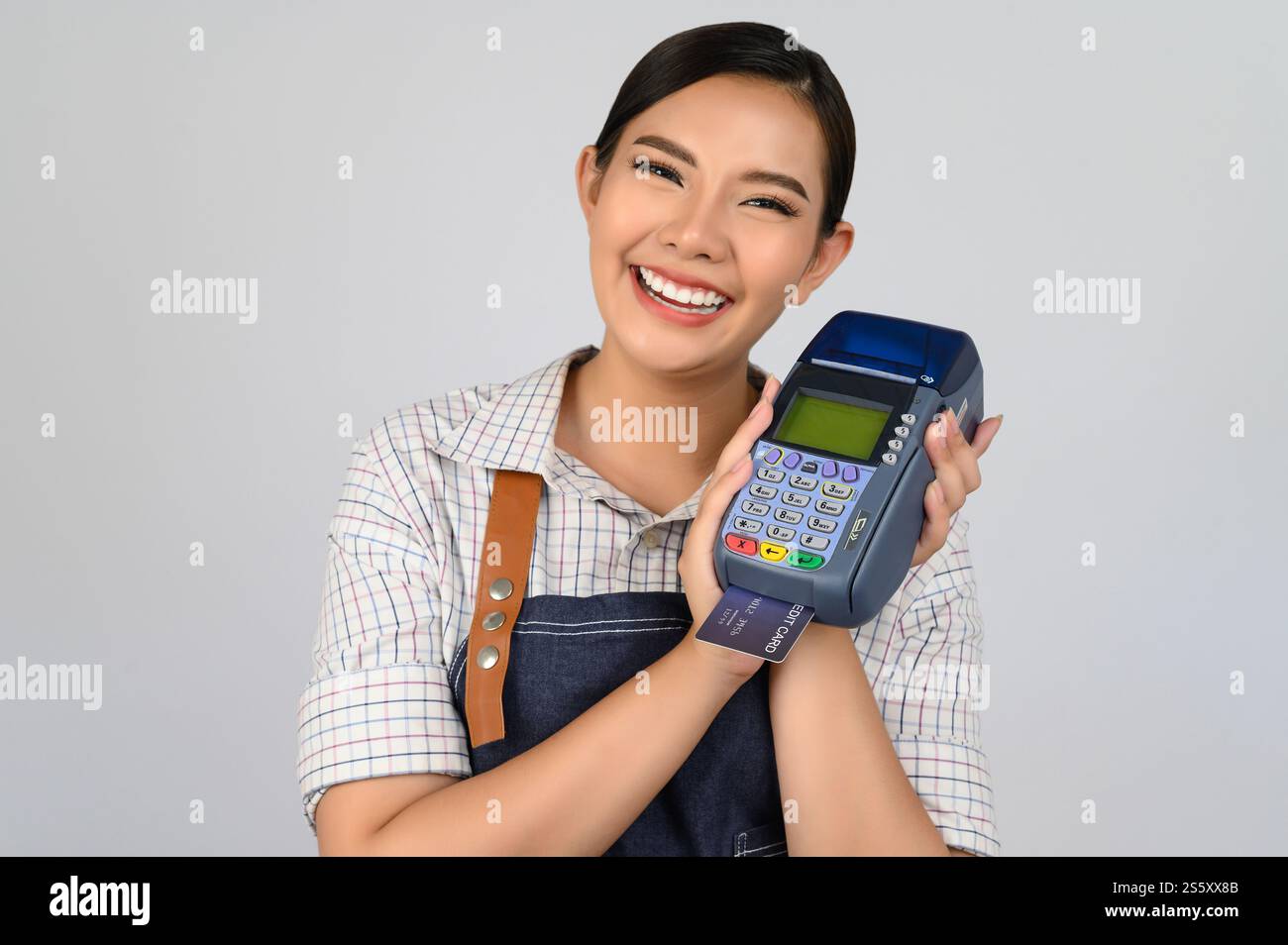 Portrait de jeune femme asiatique dans la pose uniforme de serveuse avec carte de crédit et lecteur de carte de crédit machine à la main, espace de copie pour insérer des produits pour Banque D'Images