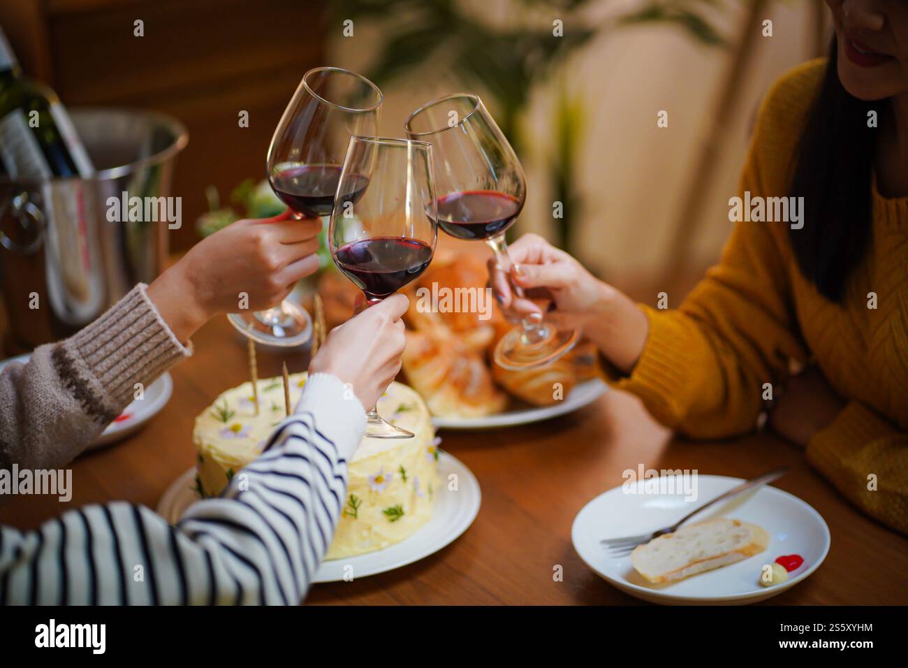 Amis joyeux appréciant la fête d'anniversaire à la maison. Amis asiatiques acclamant boire du vin rouge pour célébrer Noël ou la fête du nouvel an. Banque D'Images