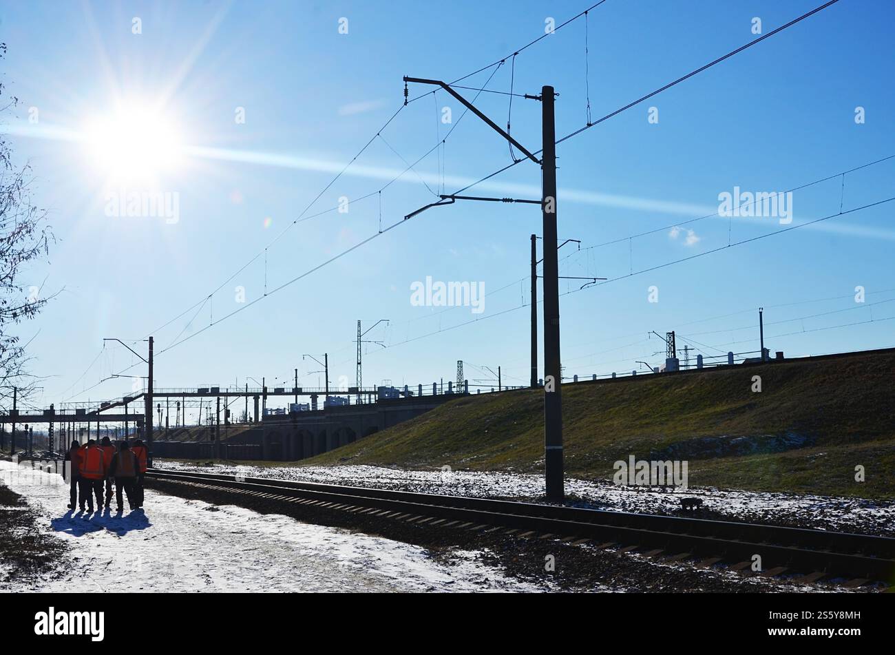 Plusieurs cheminots en signalant des uniformes orange sales sont sur la route à côté de la ligne de chemin de fer. L'équipe du train se rend au travail en hiver ensoleillé Banque D'Images Plusieurs cheminots en signalant des uniformes orange sales sont sur la route à côté de la ligne de chemin de fer. L'équipe du train se rend au travail en hiver ensoleillé Banque D'Images
