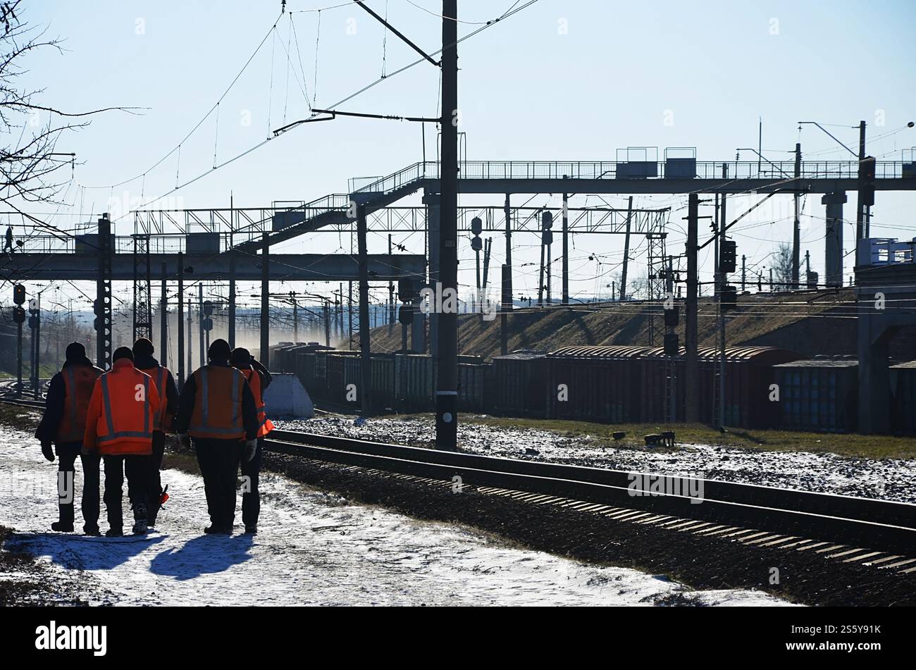 Plusieurs cheminots en signalant des uniformes orange sales sont sur la route à côté de la ligne de chemin de fer. L'équipe du train se rend au travail en hiver ensoleillé Banque D'Images Plusieurs cheminots en signalant des uniformes orange sales sont sur la route à côté de la ligne de chemin de fer. L'équipe du train se rend au travail en hiver ensoleillé Banque D'Images