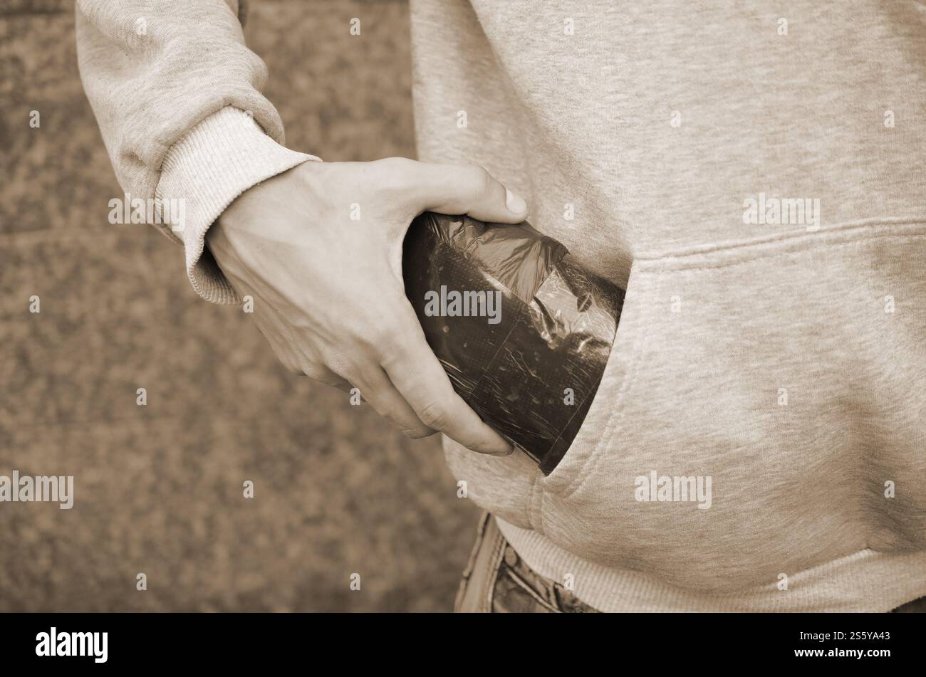 Trafiquant de drogue prenant sac avec de la cocaïne hors de la poche du sweat à capuche sur fond de tuiles sombres en gros plan. Concept de trafic de stupéfiants. Toxicomanie. Trafiquant de drogue Banque D'Images