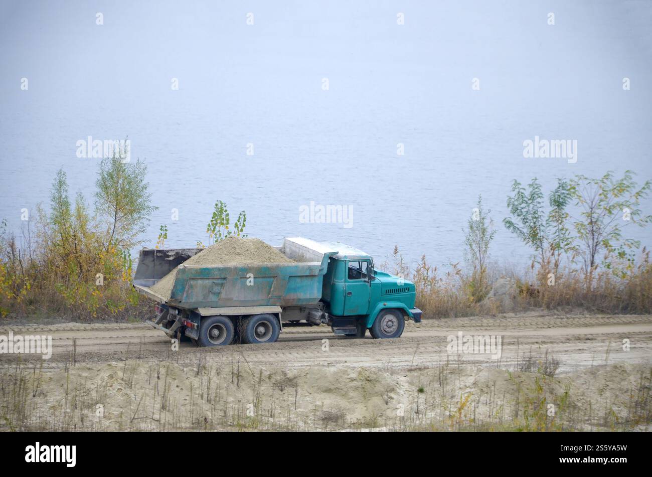 Le camion à benne basculante transporte du sable et d'autres minéraux dans la carrière minière. Industrie lourde et transport des ressources. Camion à benne basculante transporte du sable et autre Banque D'Images