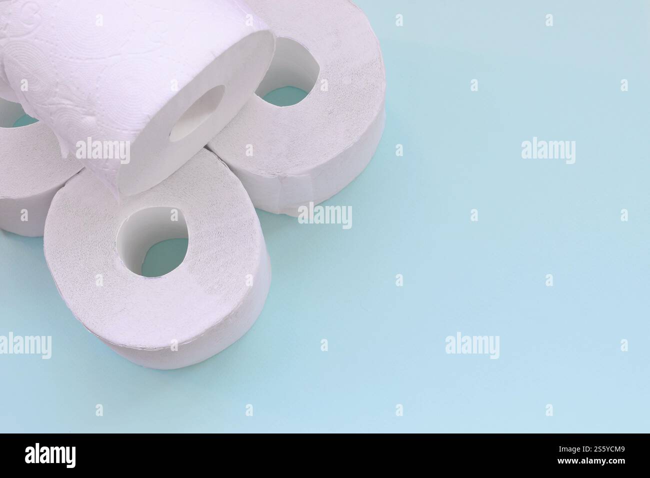 Concept de panique pandémique du coronavirus. Peu de nouveaux rouleaux de papier toilette sur fond bleu clair. Composition à plat minimaliste avec espace de copie Banque D'Images