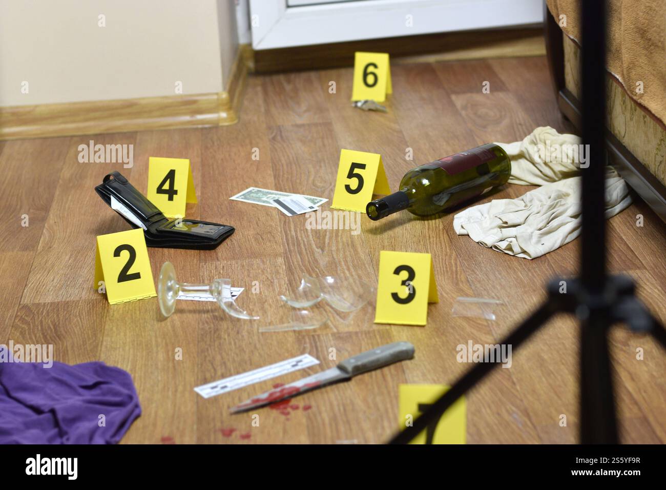 Enquête sur les lieux du crime - numérotation des preuves après le meurtre dans l'appartement. Verre cassé de vin, couteau avec des vêtements, portefeuille et bouteille comme Banque D'Images