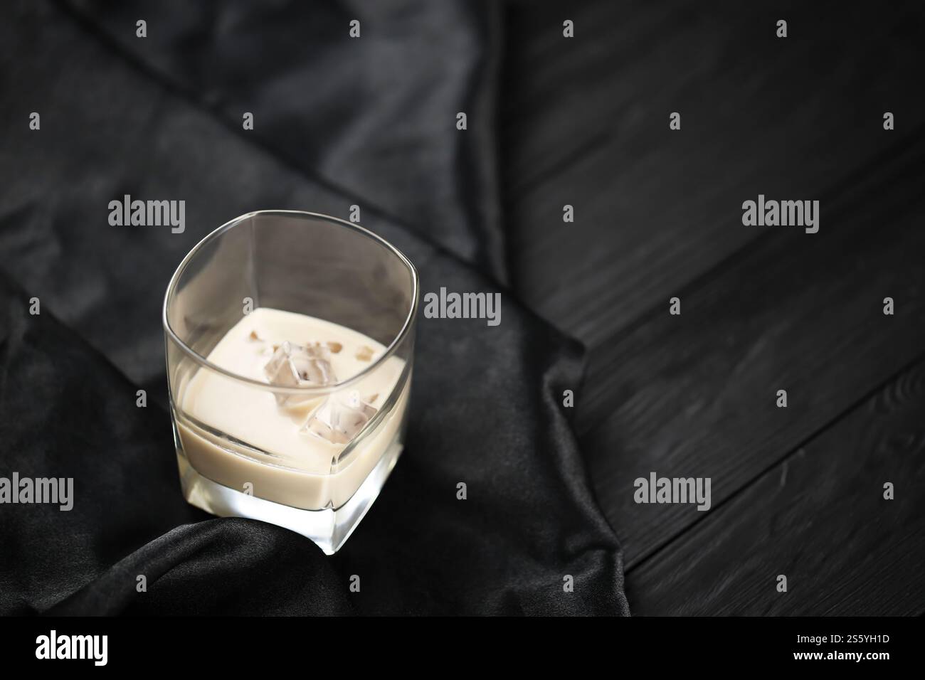 Verre de liqueur baileys de crème irlandaise avec glaçons sur toile sombre et arrière-plan de table en bois. Cocktail d'alcool haut de gamme fait maison. Placer pour Banque D'Images
