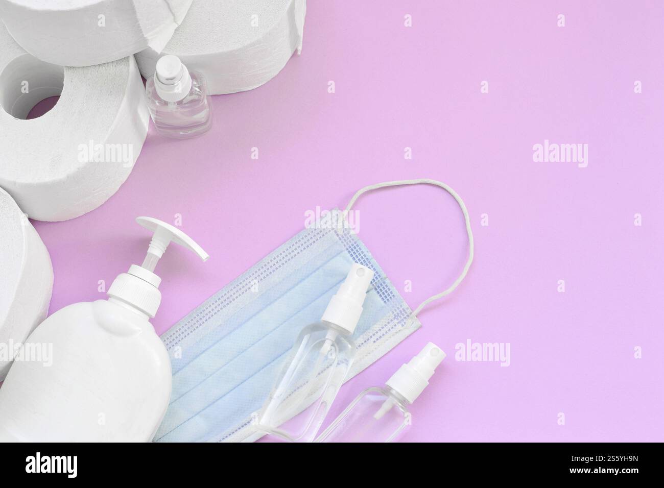 Ensemble d'articles importants pour les heures de quarantaine COVID-19. Papier toilette avec masque facial chirurgical et désinfectant pour les mains avec bouteille de savon liquide sur lilas Banque D'Images