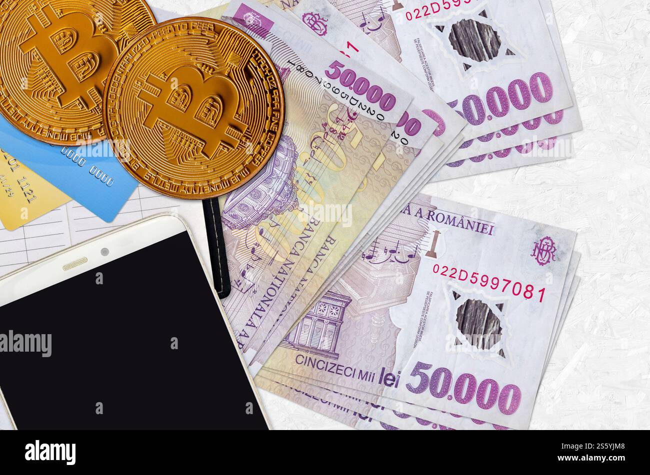 50000 billets de leu roumains et bitcoins dorés avec smartphone et cartes de crédit. Concept d'investissement en crypto-monnaie. Minage ou trading de crypto Banque D'Images
