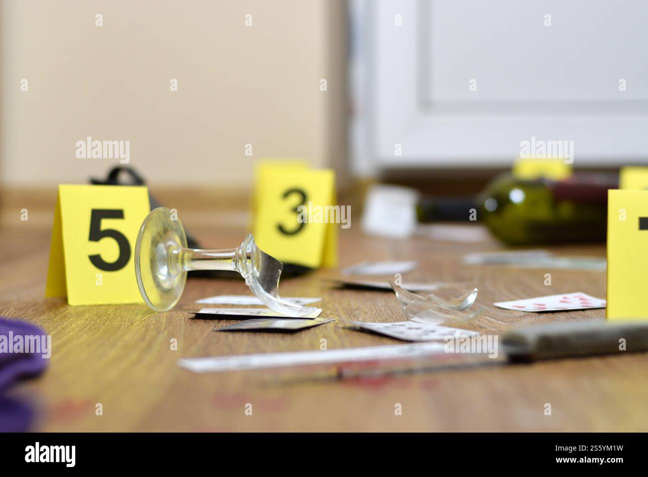 Enquête sur les lieux du crime - numérotation des preuves après le meurtre dans l'appartement. Verre de vin cassé, couteau et bouteille comme preuve de gros plan. Banque D'Images