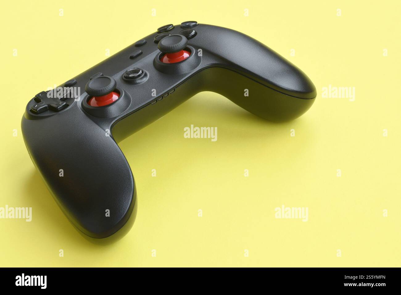 Contrôleur de jeu vidéo noir moderne sur fond jaune gros plan. Jeu vidéo speedrun concept ou défi de compétition Esports. Vidéo noire moderne Banque D'Images