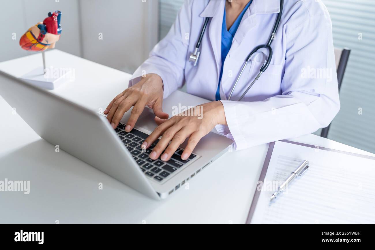 Cardiologue soutient le cœur femme asiatique senior médecin portant des lunettes et uniforme. portrait de vieilles femmes asiatiques matures professionnelles médicales. Banque D'Images