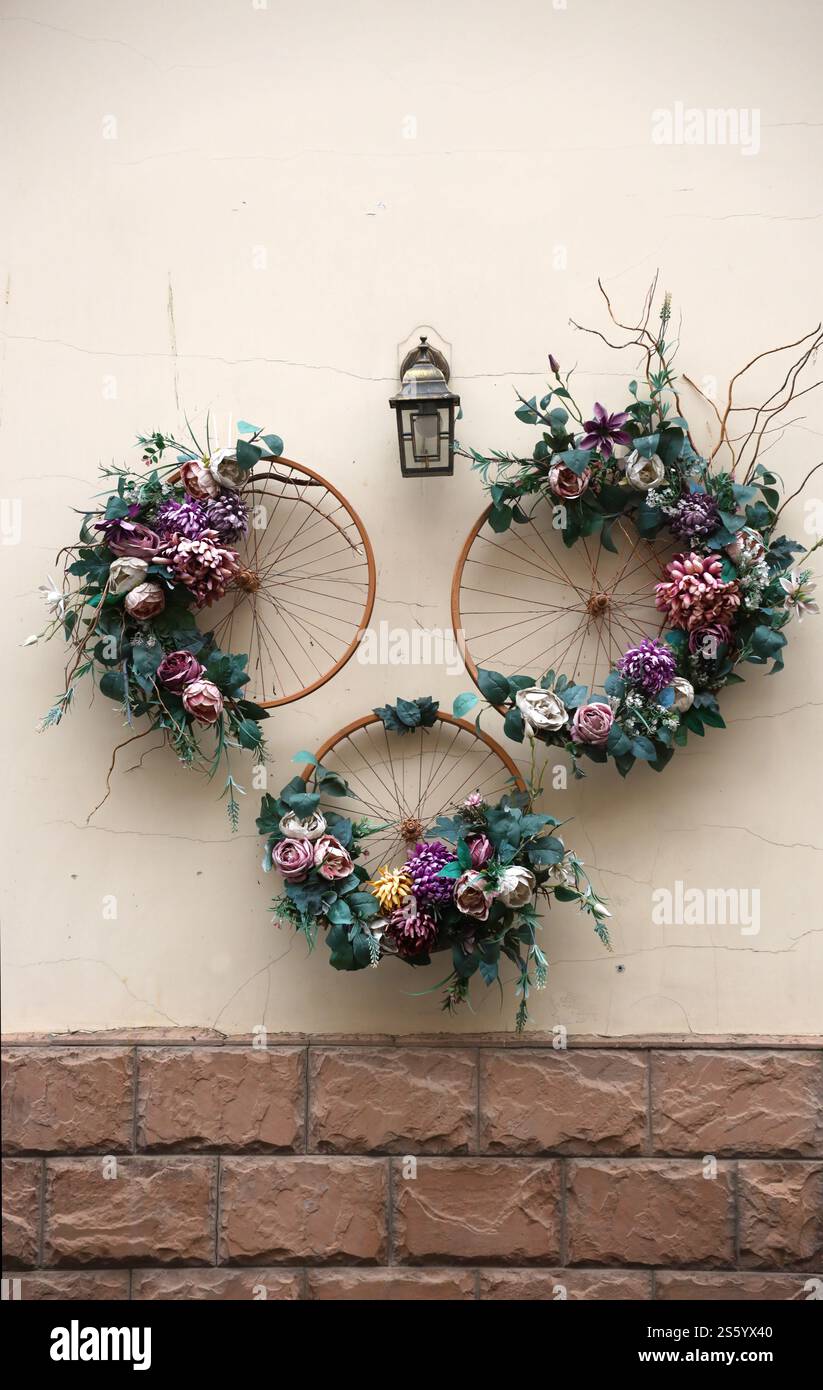 Décoration objet d'art urbain de roues de vélo et fleurs élégantes colorées sur le mur. Décoration objet d'art urbain de roues de vélo et de fleurs sur Banque D'Images