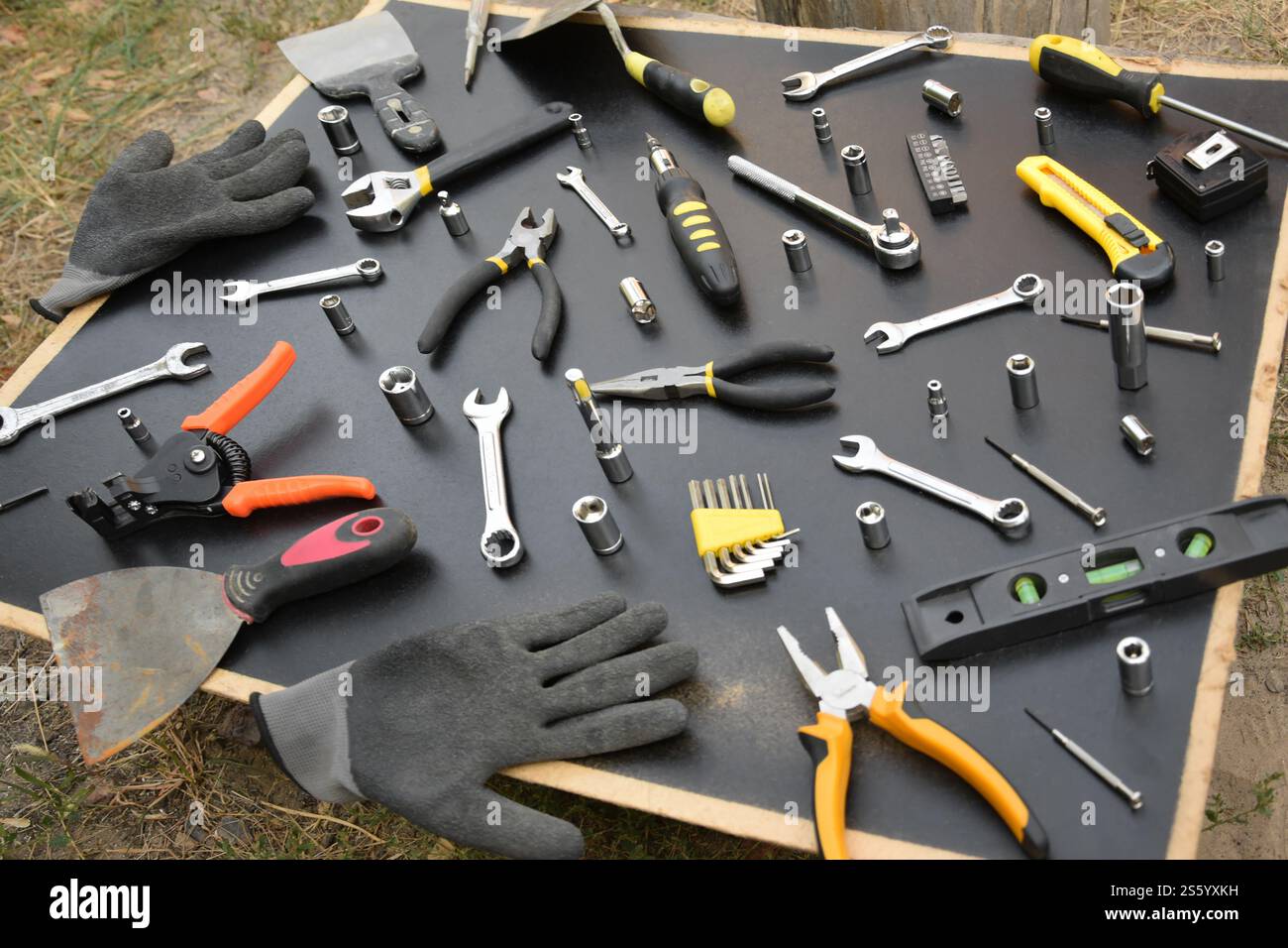Kit d'outils bricoleur sur table en bois noir. De nombreuses clés et tournevis, pilers et autres outils pour tout type de travaux de réparation ou de construction. Banque D'Images