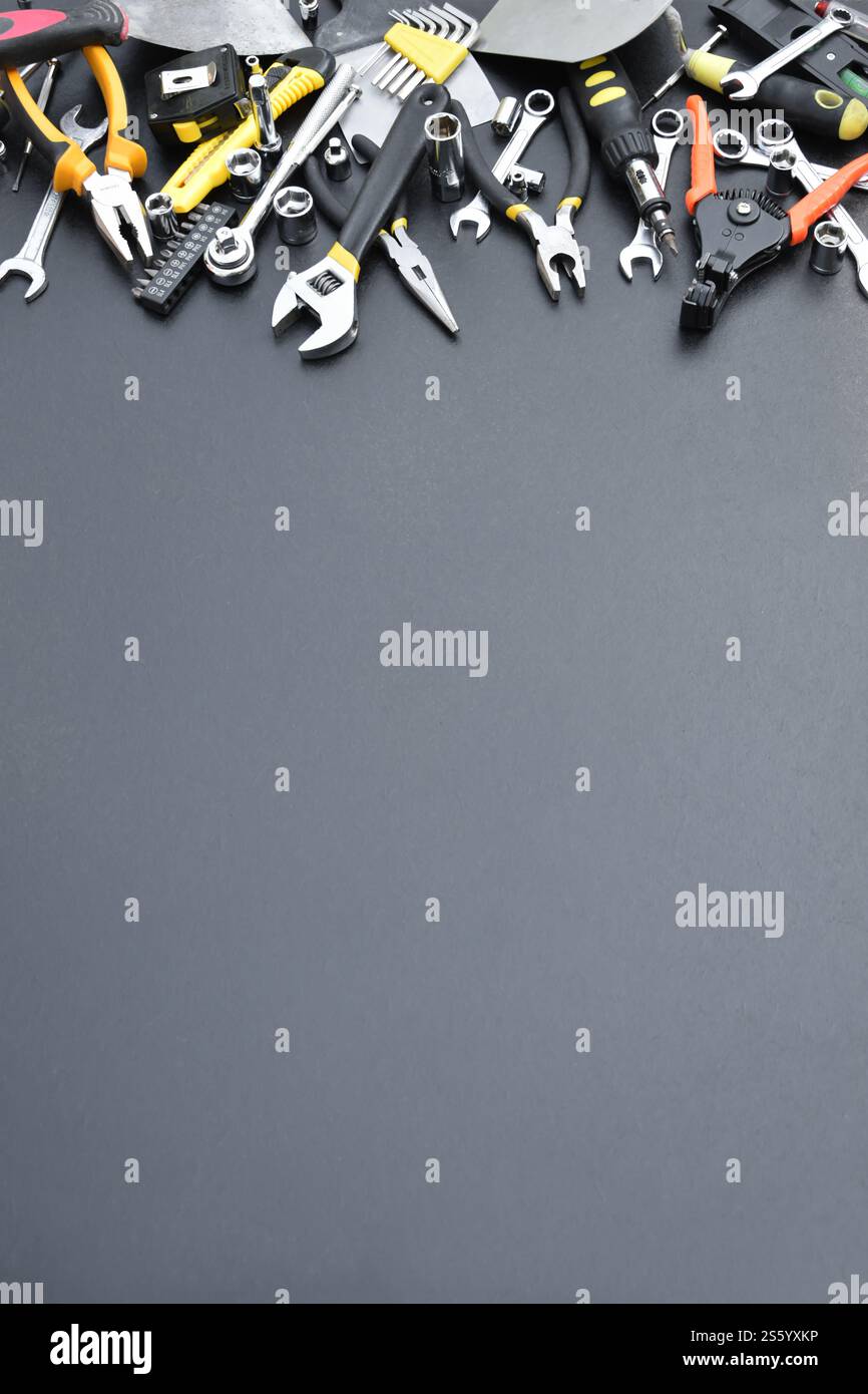 Kit d'outils bricoleur sur table en bois noir. De nombreuses clés et tournevis, pilers et autres outils pour tout type de travaux de réparation ou de construction. Banque D'Images