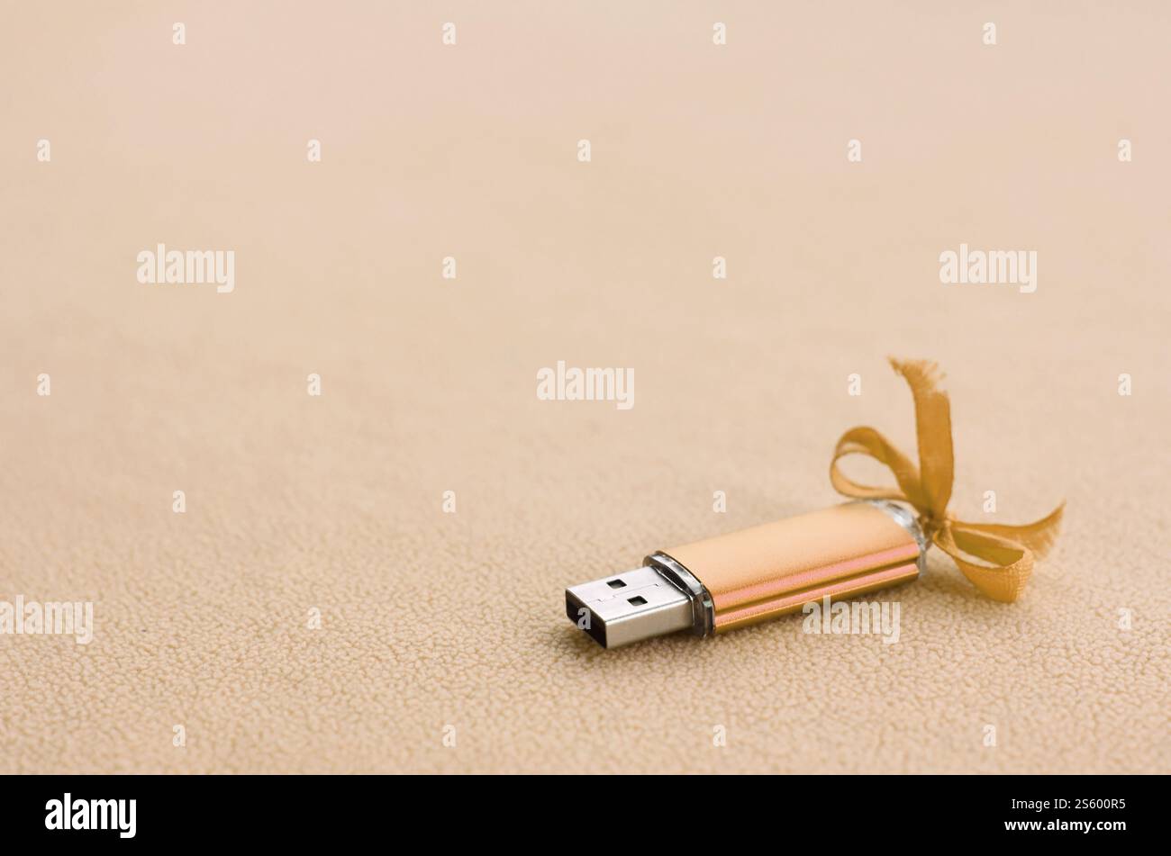 Carte mémoire flash usb orange avec un noeud bleu repose sur une couverture de tissu polaire orange clair doux et fourré. Design de cadeau féminin classique pour un souvenir Banque D'Images