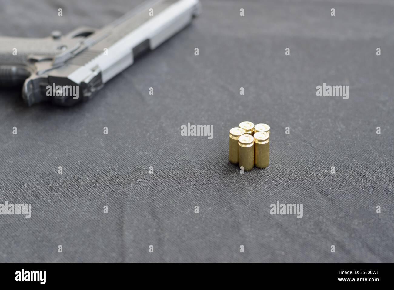 balles de 9mm et pistolet reposent sur un tissu noir. Un ensemble d'objets de tir ou un kit d'auto-défense. Obus dorés près d'une arme de poing. balles de 9mm et pistolet Banque D'Images