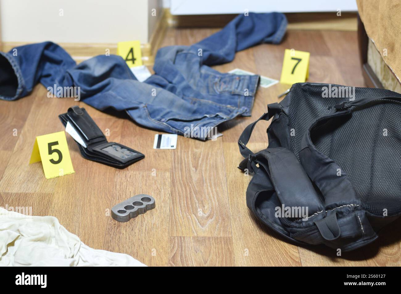 Enquête sur la scène de crime - numérotation des preuves après le meurtre dans l'appartement. Knuckle en laiton, portefeuille et vêtements avec des marqueurs de preuve à fermer Banque D'Images