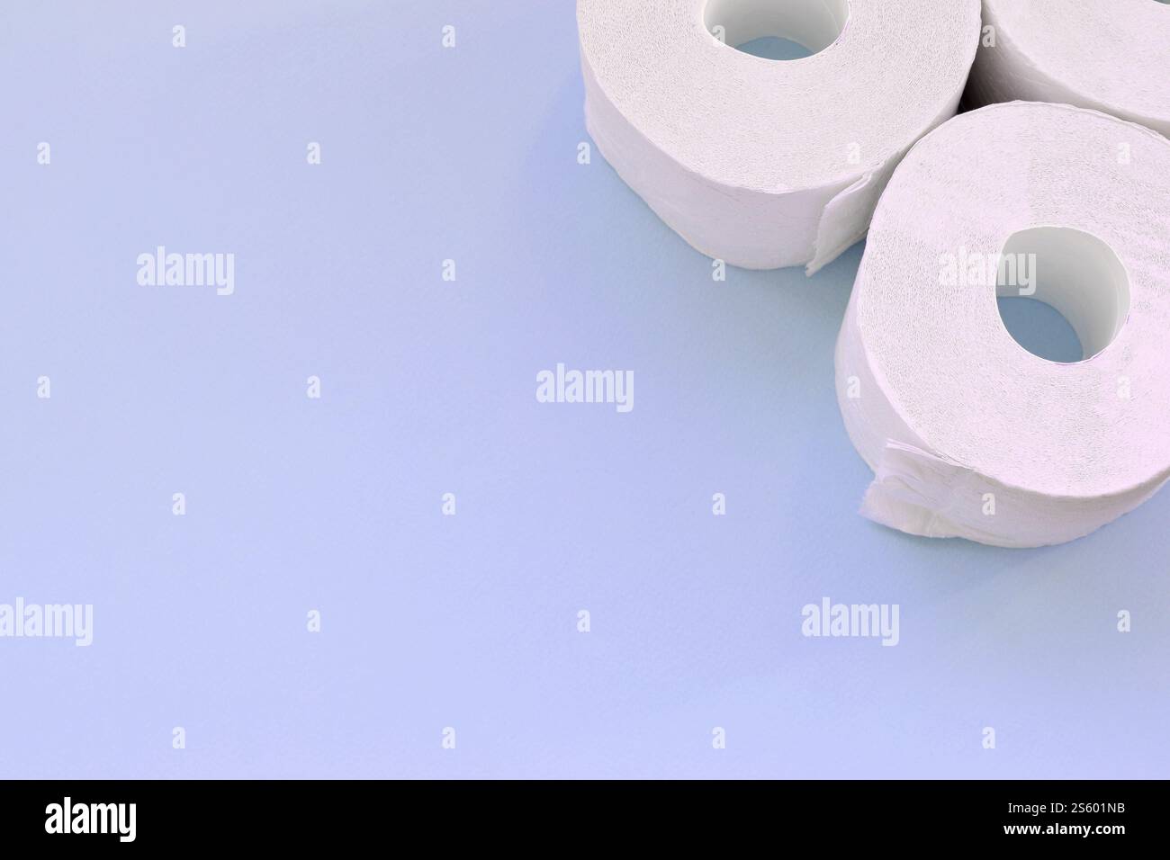 Concept de panique pandémique du coronavirus. Peu de nouveaux rouleaux de papier toilette sur fond bleu clair. Composition à plat minimaliste avec espace de copie Banque D'Images