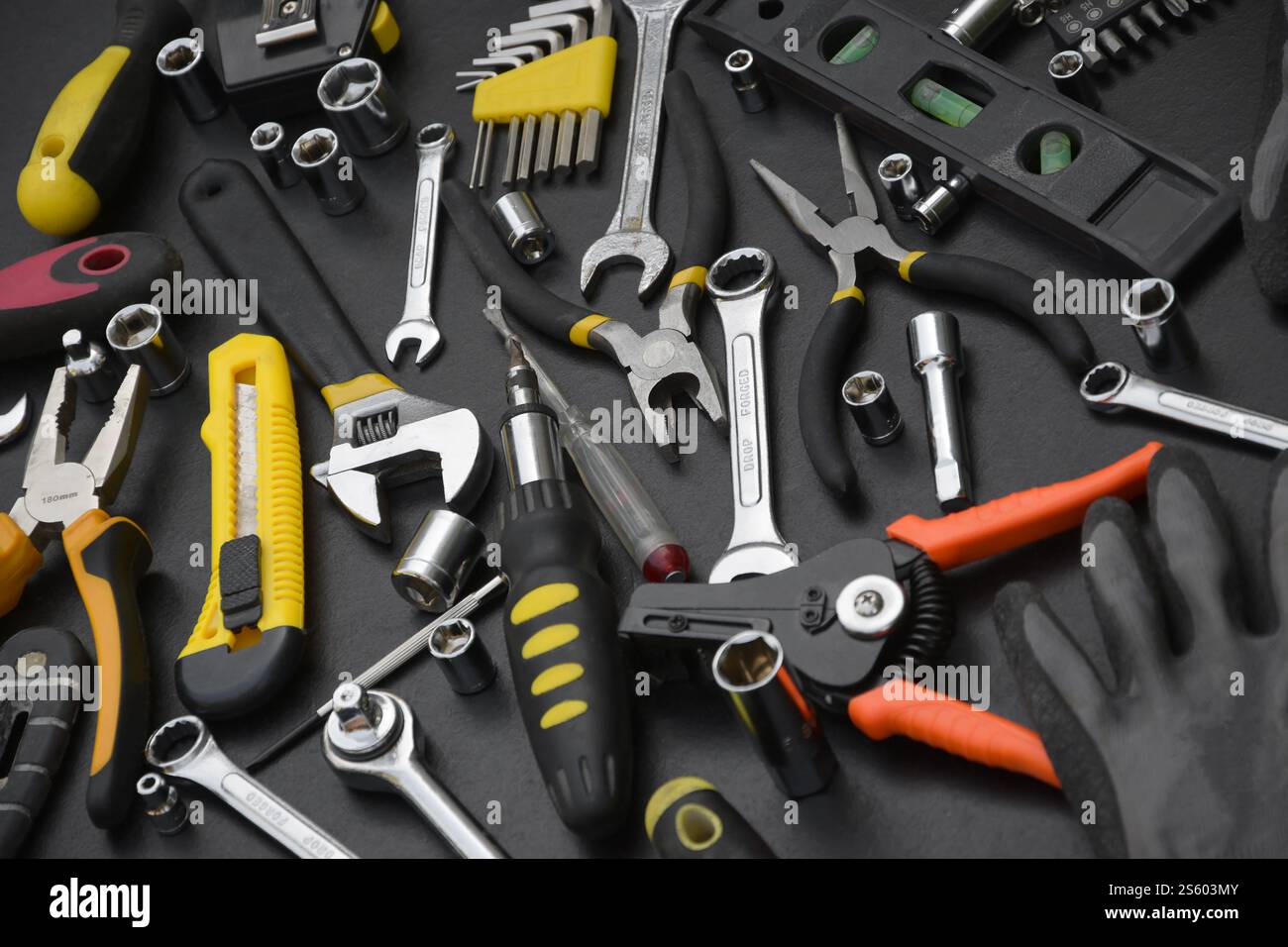 Kit d'outils bricoleur sur table en bois noir. De nombreuses clés et tournevis, pilers et autres outils pour tout type de travaux de réparation ou de construction. Banque D'Images