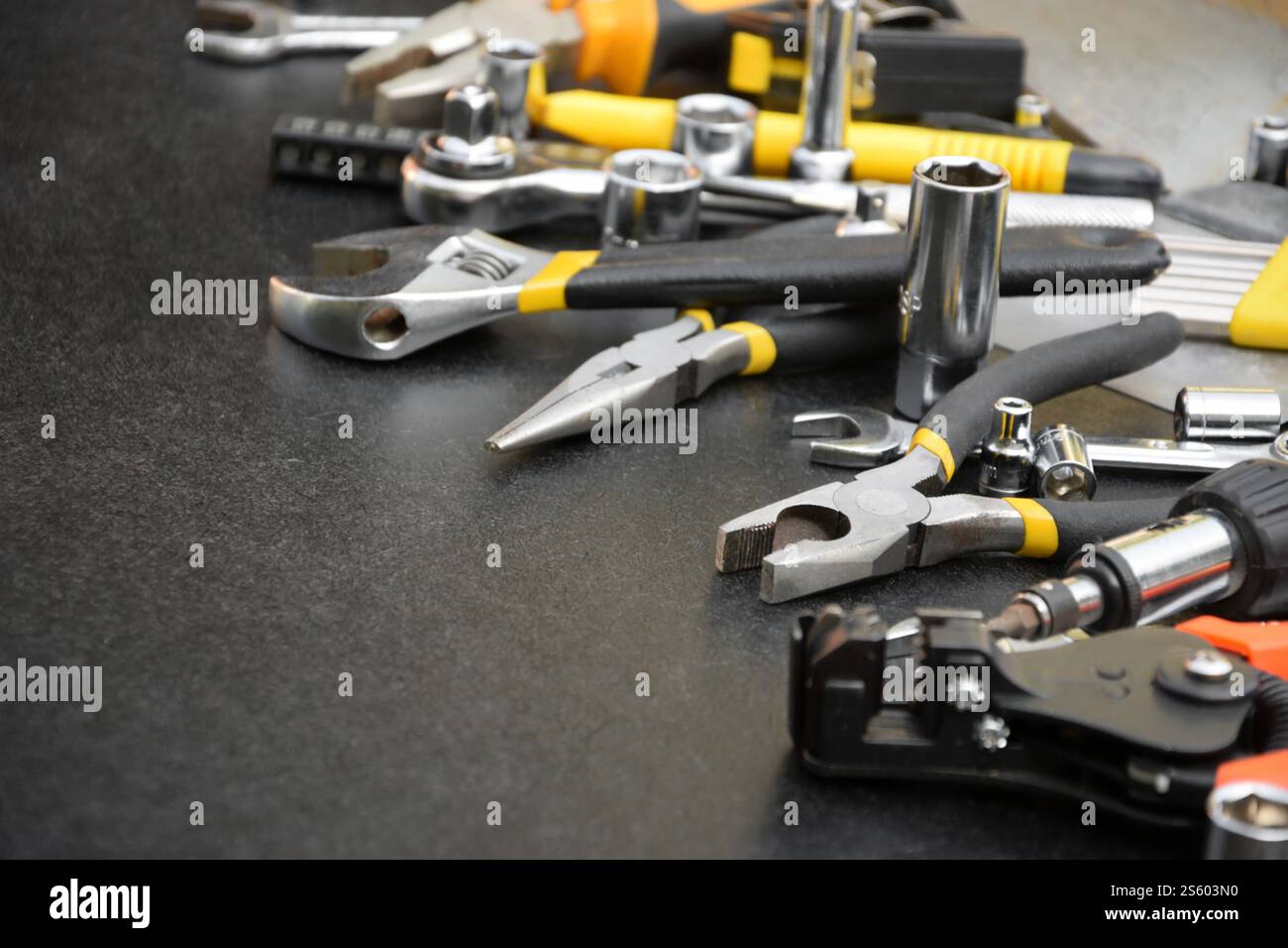 Kit d'outils bricoleur sur table en bois noir. De nombreuses clés et tournevis, pilers et autres outils pour tout type de travaux de réparation ou de construction. Banque D'Images