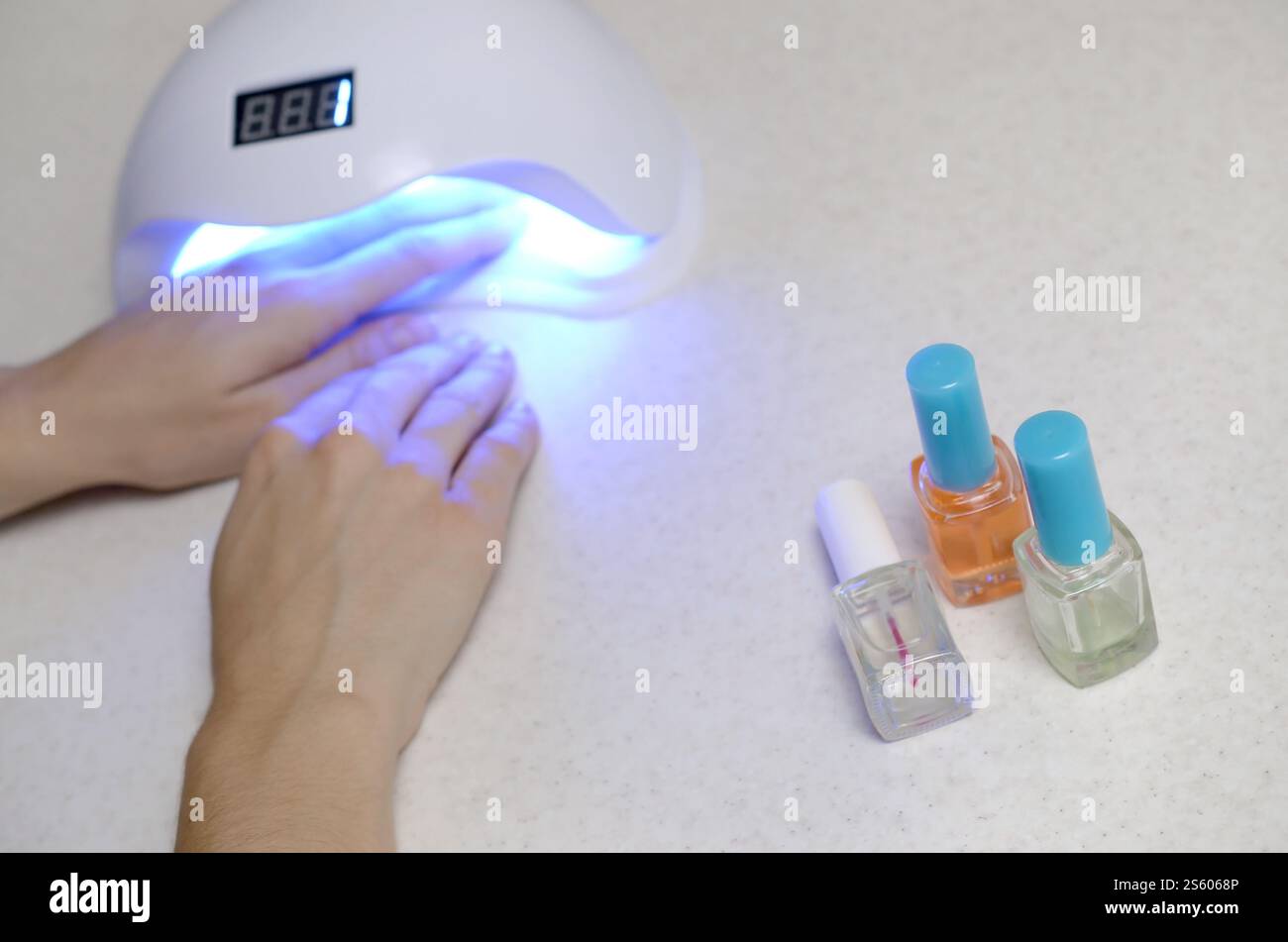 Mains de la jeune femme à la procédure de manucure gros plan sur fond blanc. Processus de vernis à ongles femme. Femelle utilisant la lampe LED uv shellac pour rapide Banque D'Images