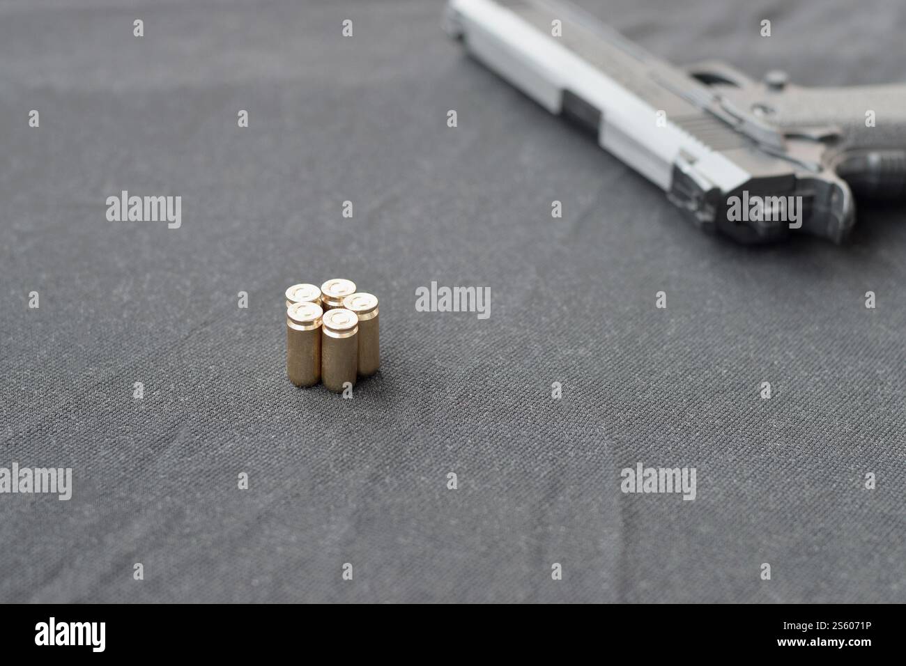 balles de 9mm et pistolet reposent sur un tissu noir. Un ensemble d'objets de tir ou un kit d'auto-défense. Obus dorés près d'une arme de poing. balles de 9mm et pistolet Banque D'Images