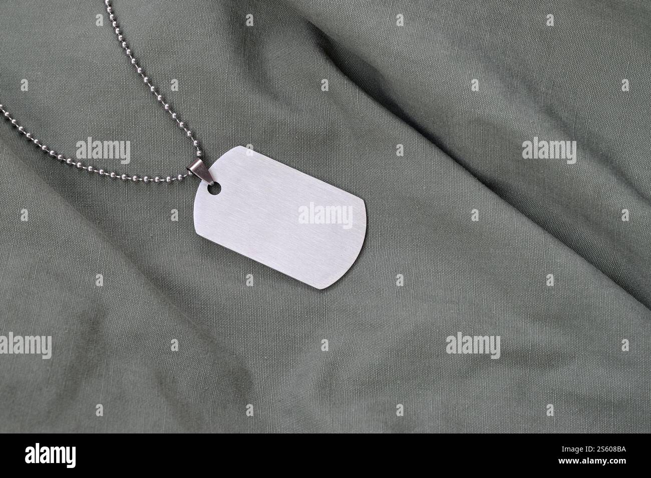 Perles militaires argentées avec étiquette de chien sur uniforme de fatigue vert foncé. Jeton de l'armée sur la veste camouflage des soldats. Perles militaires argentées avec étiquette de chien sur sombre Banque D'Images