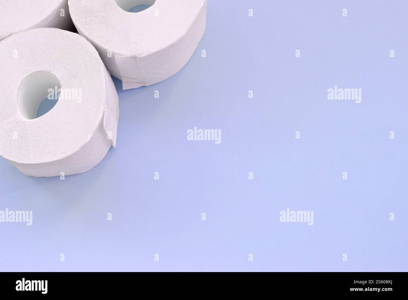 Concept de panique pandémique du coronavirus. Peu de nouveaux rouleaux de papier toilette sur fond bleu clair. Composition à plat minimaliste avec espace de copie Banque D'Images