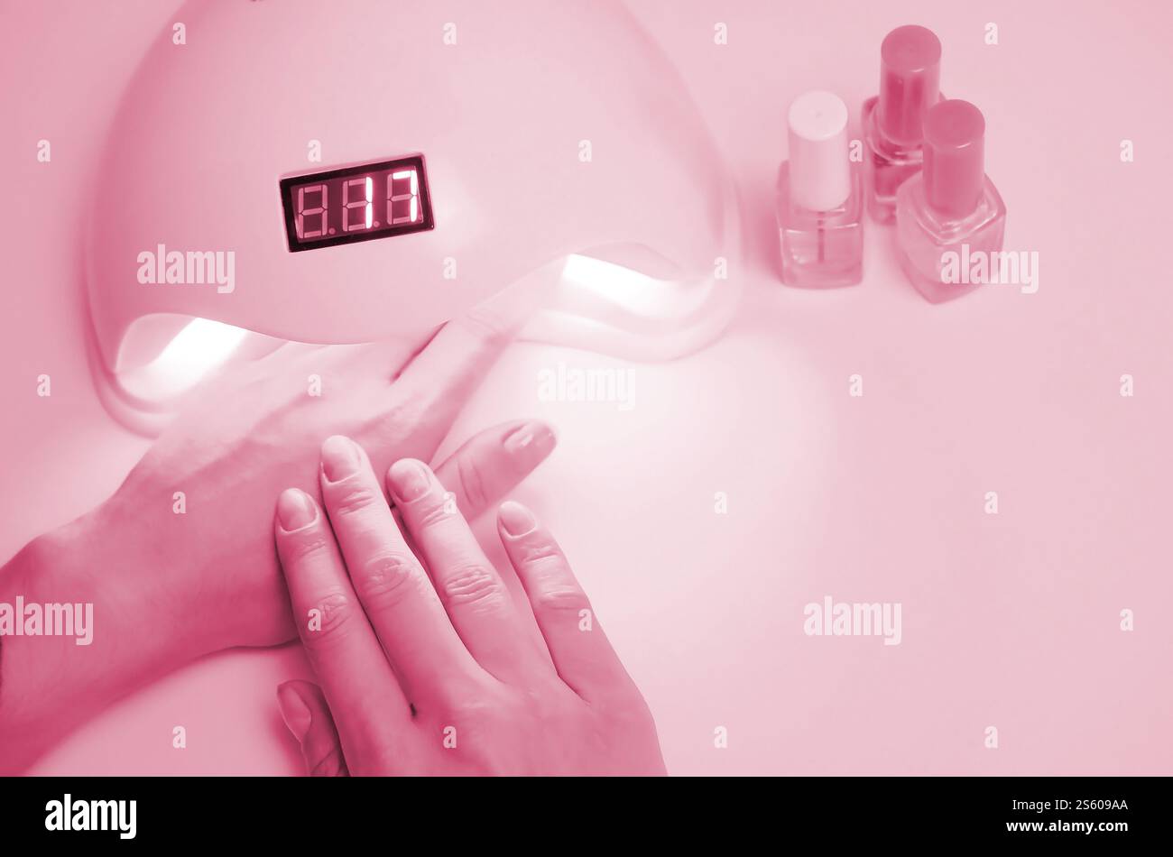 Mains de la jeune femme à la procédure de manucure gros plan sur fond rose pastel. Processus de vernis à ongles femme. Image colorée en Viva Magenta, couleur du Banque D'Images