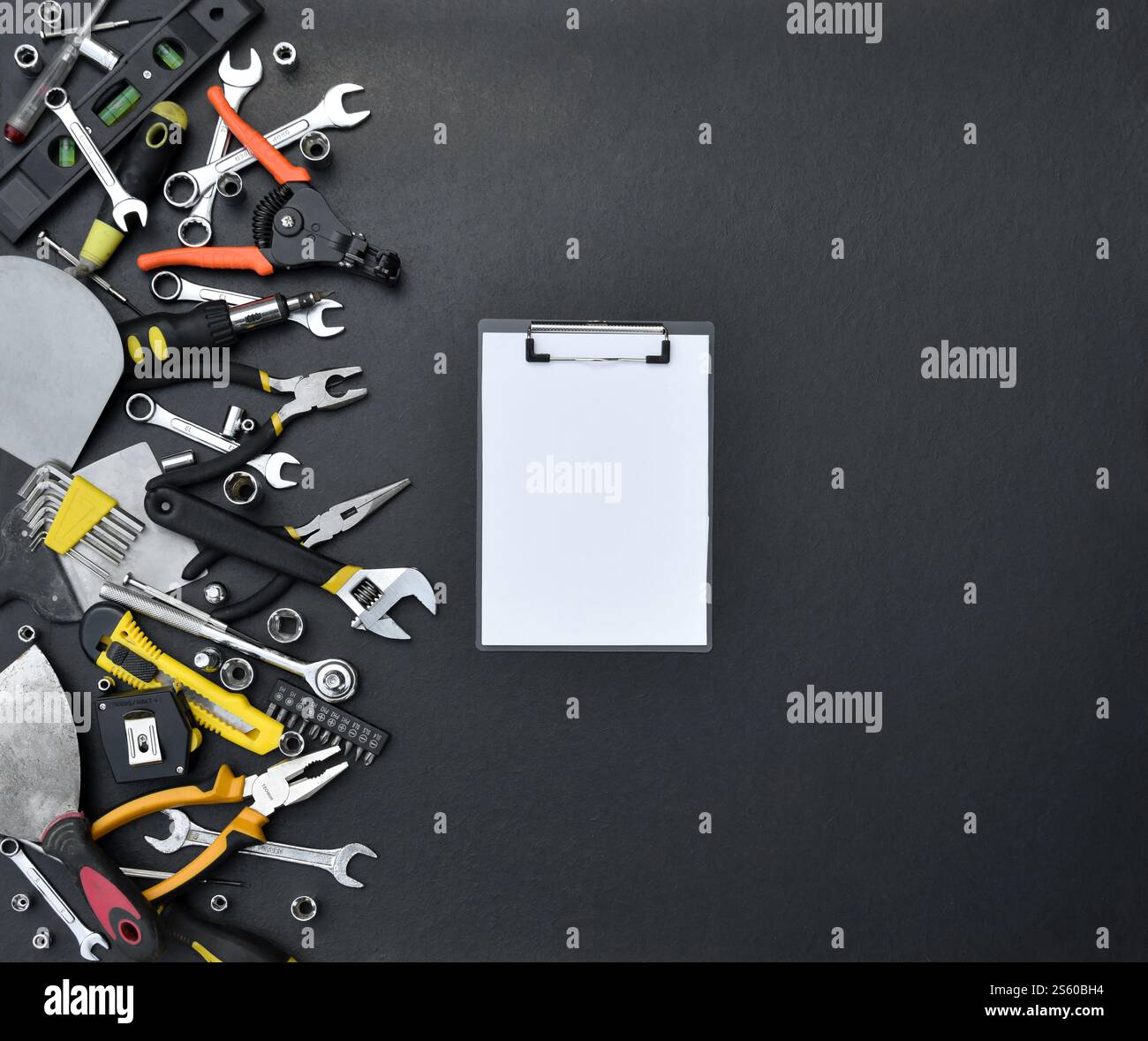 Kit d'outils bricoleur sur table en bois noir. De nombreuses clés et tournevis, pilers et autres outils pour tout type de travaux de réparation ou de construction. Banque D'Images