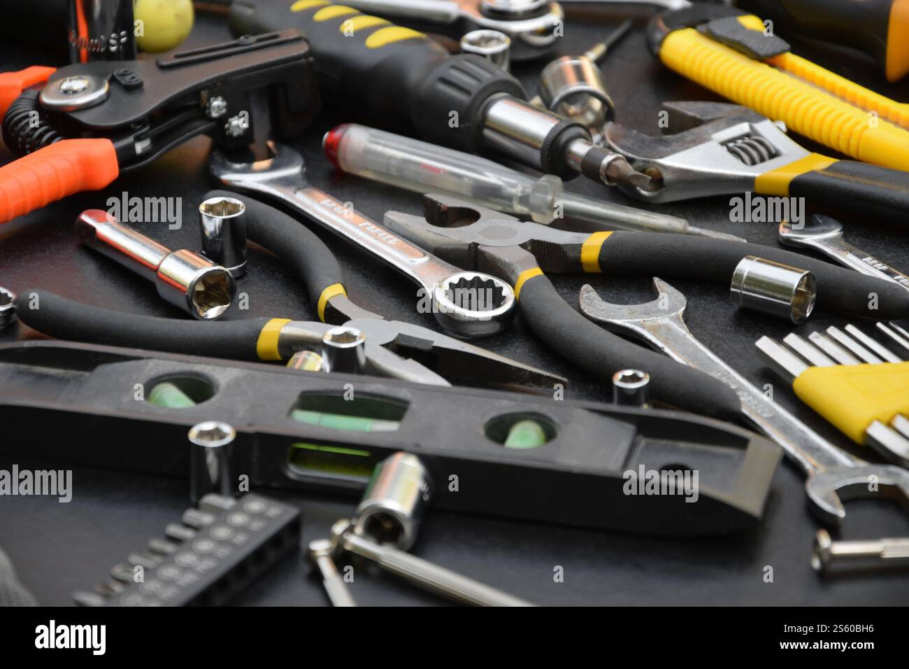 Kit d'outils bricoleur sur table en bois noir. De nombreuses clés et tournevis, pilers et autres outils pour tout type de travaux de réparation ou de construction. Banque D'Images