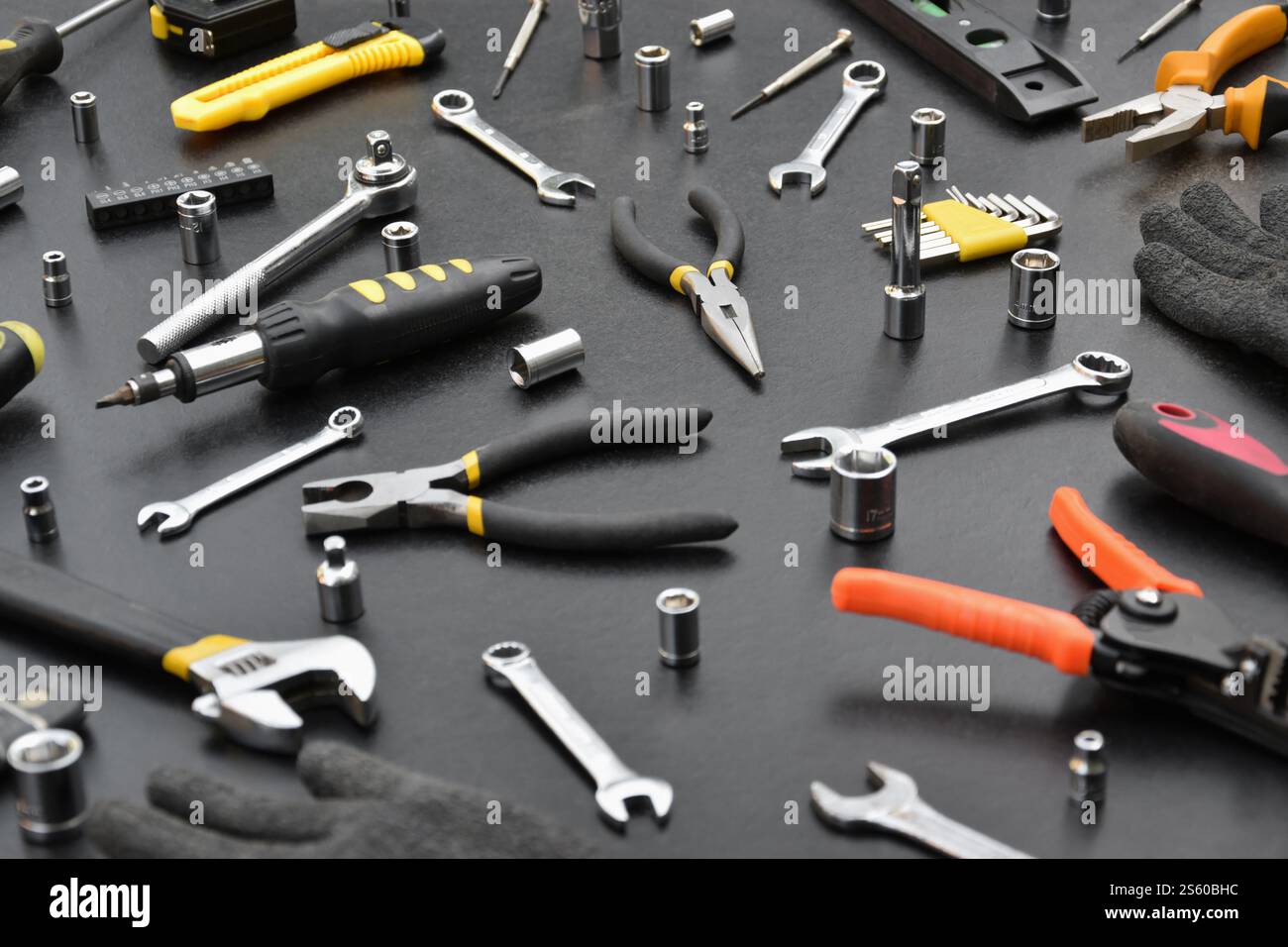 Kit d'outils bricoleur sur table en bois noir. De nombreuses clés et tournevis, pilers et autres outils pour tout type de travaux de réparation ou de construction. Banque D'Images